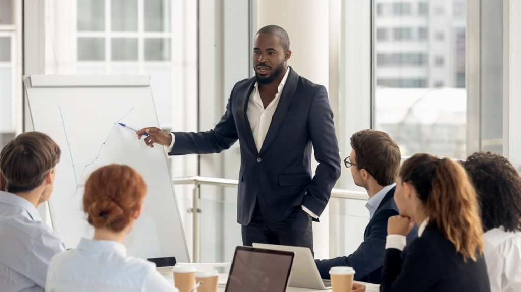políticas de inclusão racial a imagem mostra um homem jovem e negro conduzindo uma reunião de trabalho